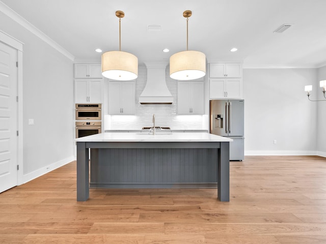 kitchen with pendant lighting, stainless steel appliances, light countertops, and custom range hood