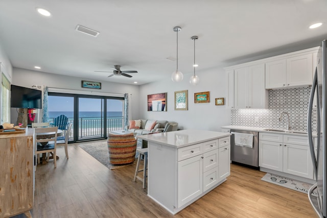 kitchen featuring light hardwood / wood-style flooring, stainless steel appliances, decorative backsplash, a water view, and ceiling fan