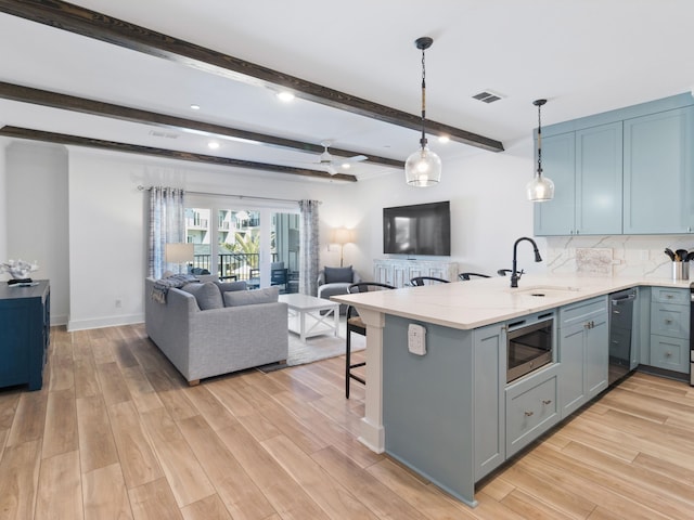 kitchen featuring a kitchen bar, sink, light hardwood / wood-style flooring, stainless steel microwave, and kitchen peninsula