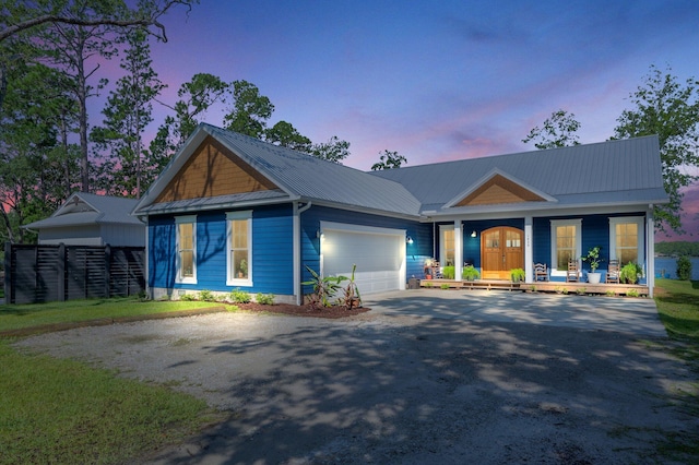 view of front of home with a garage, metal roof, driveway, and a porch