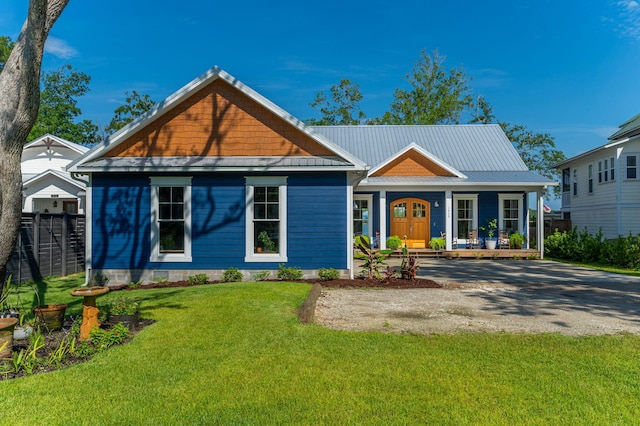 view of front of home featuring metal roof, a porch, a front lawn, and fence