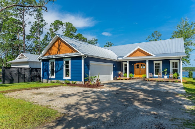 view of front of property featuring driveway, a garage, metal roof, covered porch, and fence