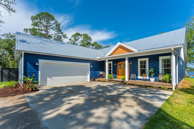 ranch-style home featuring a porch, concrete driveway, metal roof, and a garage