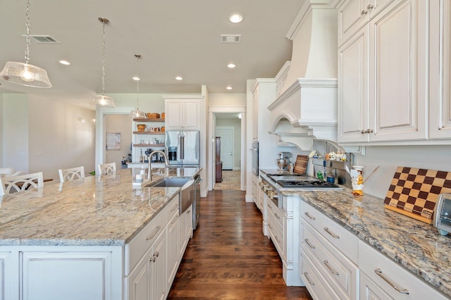 kitchen featuring white cabinets, hanging light fixtures, a large island with sink, and a kitchen breakfast bar