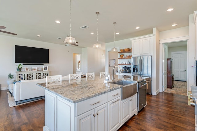 kitchen with stainless steel appliances, white cabinetry, a center island with sink, and a sink