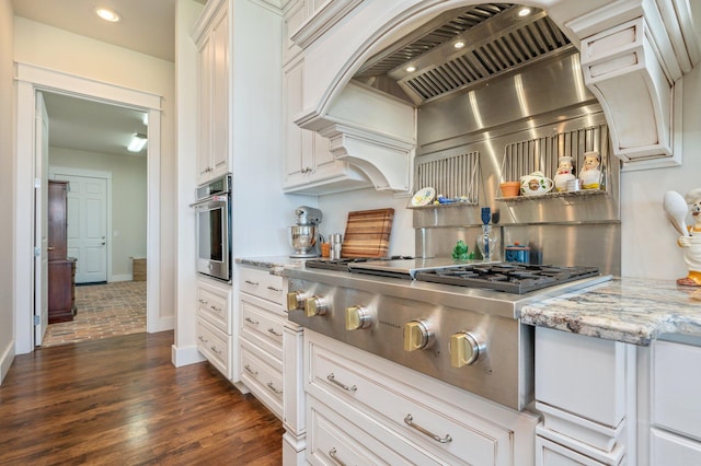 kitchen featuring light stone counters, stainless steel appliances, dark wood-type flooring, baseboards, and exhaust hood