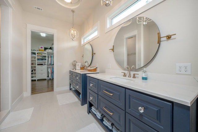 bathroom with baseboards, visible vents, tile patterned floors, a spacious closet, and vanity