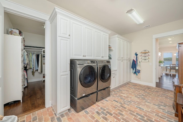 laundry area featuring brick floor, baseboards, visible vents, and separate washer and dryer