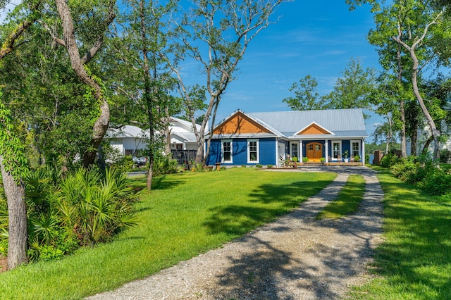 view of front facade with a front yard, metal roof, and driveway