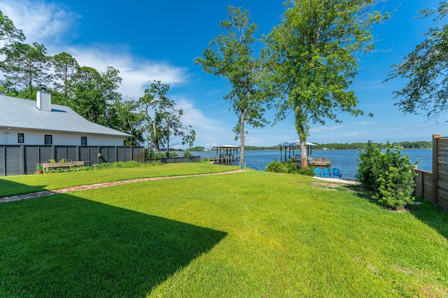 view of yard with a water view, a dock, and fence