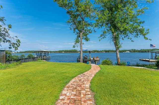 view of yard with a boat dock, a water view, and fence