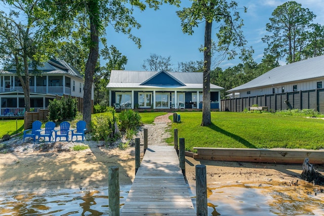 rear view of property featuring fence, metal roof, and a yard