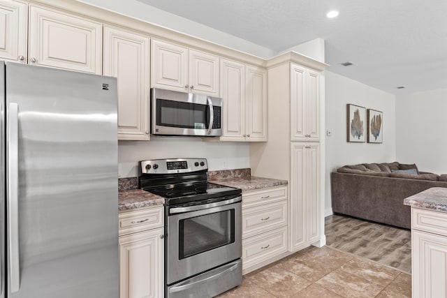 kitchen featuring dark stone countertops, cream cabinets, and stainless steel appliances