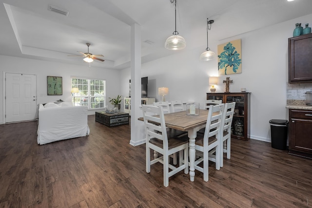 dining area featuring ceiling fan, dark wood-type flooring, and a tray ceiling