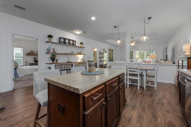 kitchen featuring pendant lighting, dark hardwood / wood-style floors, ceiling fan, dark brown cabinets, and a kitchen island