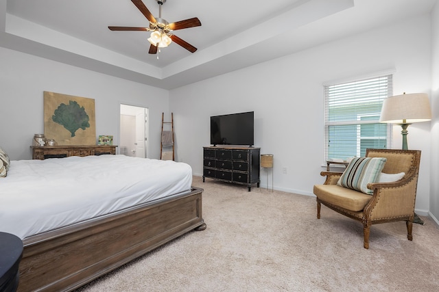 bedroom with ceiling fan, a raised ceiling, and light carpet