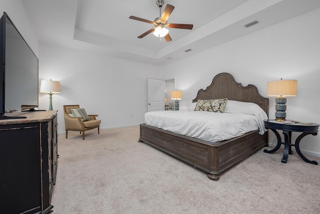 carpeted bedroom featuring a raised ceiling and ceiling fan