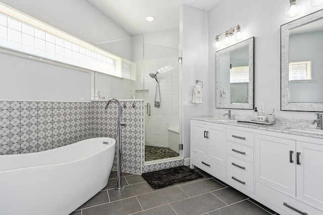 bathroom featuring a stall shower, tile patterned flooring, a sink, and a freestanding bath