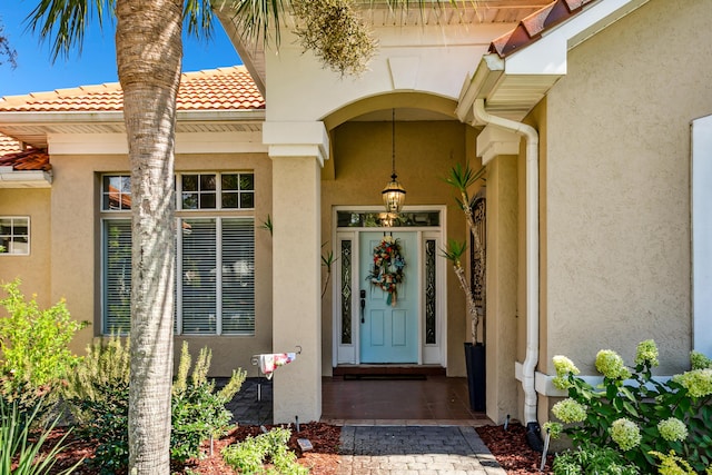 view of exterior entry with a tile roof and stucco siding