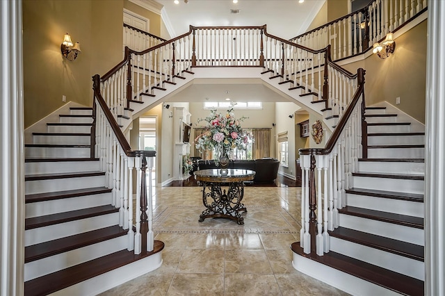 foyer with a towering ceiling, tile flooring, and crown molding