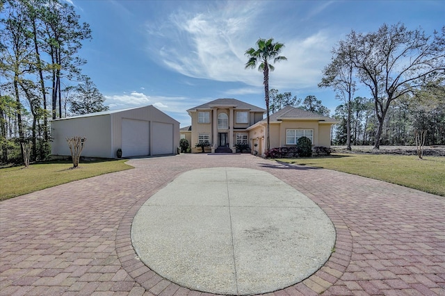 view of front of property featuring an outdoor structure, a garage, and a front lawn