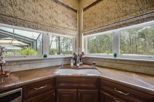 kitchen featuring stone countertops, sink, and dark brown cabinets