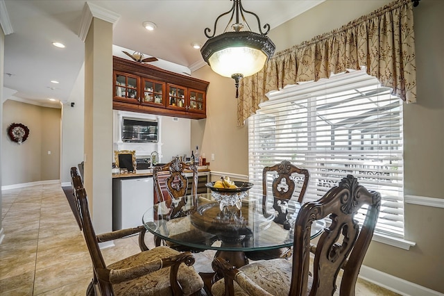 dining space featuring a healthy amount of sunlight, light tile floors, and crown molding