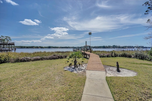 view of home's community with a lawn, a water view, and a dock