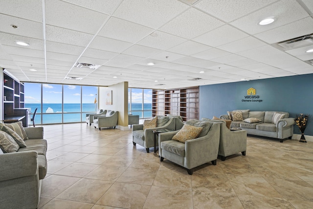 living room featuring a drop ceiling, expansive windows, and a water view