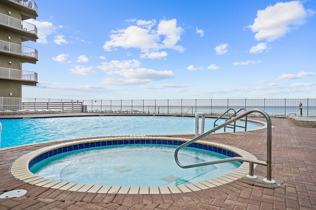 view of pool featuring a water view and a hot tub