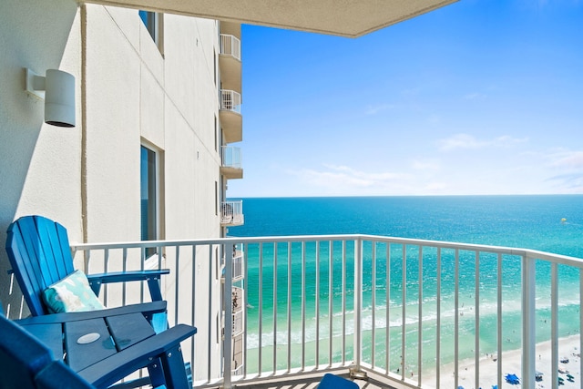 balcony with a water view and a view of the beach