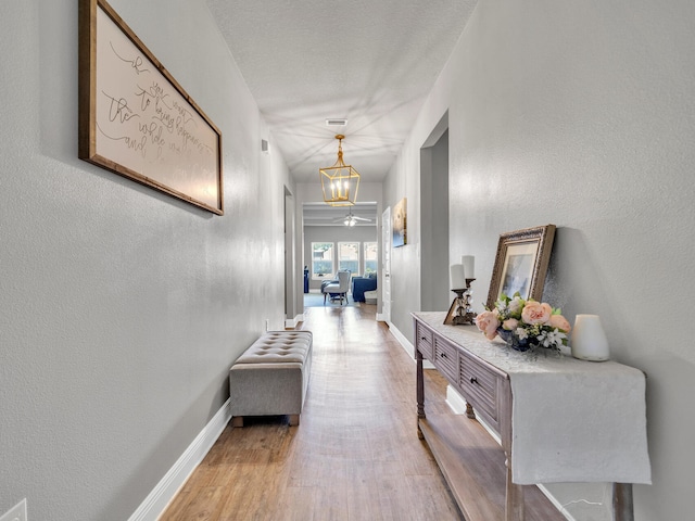 corridor with light hardwood / wood-style flooring and a notable chandelier