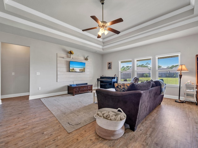 living room with a raised ceiling, ornamental molding, ceiling fan, and hardwood / wood-style flooring