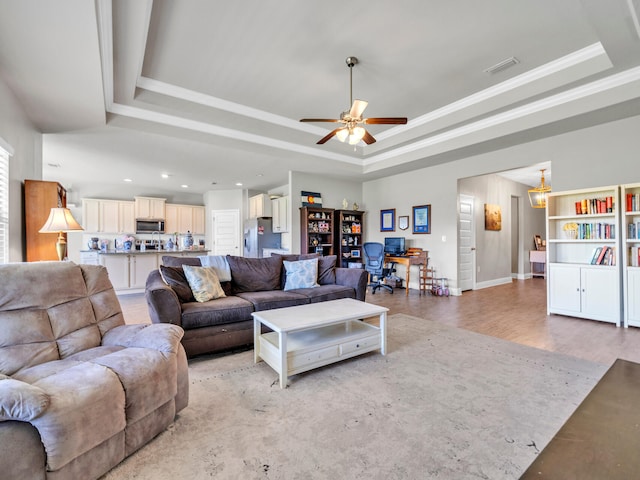 living room featuring ornamental molding, a tray ceiling, ceiling fan, and light hardwood / wood-style flooring