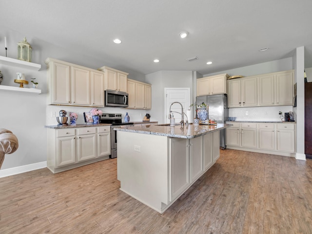 kitchen with light hardwood / wood-style flooring, stainless steel appliances, an island with sink, and sink