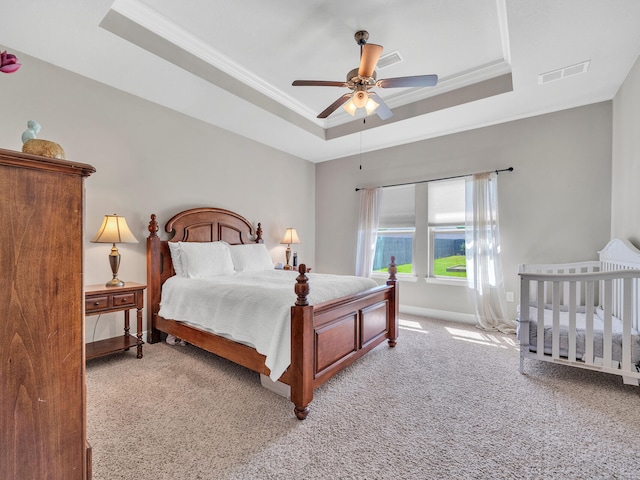 carpeted bedroom featuring ceiling fan, a raised ceiling, and crown molding