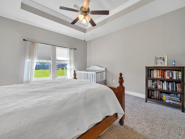 bedroom with ceiling fan, a raised ceiling, carpet floors, and crown molding