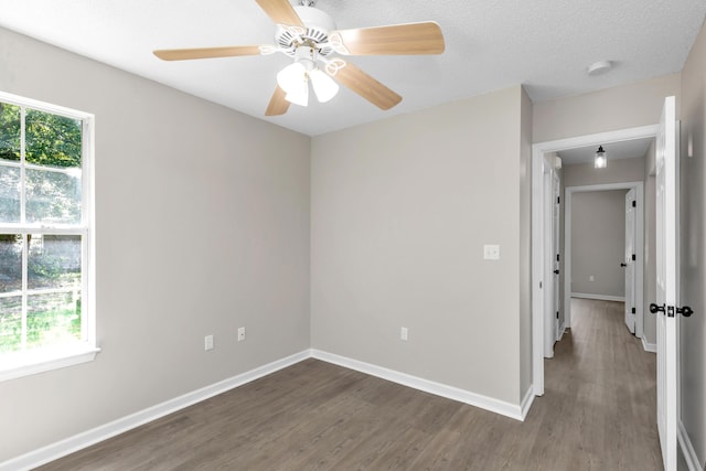 unfurnished room with ceiling fan, dark wood-type flooring, and a textured ceiling