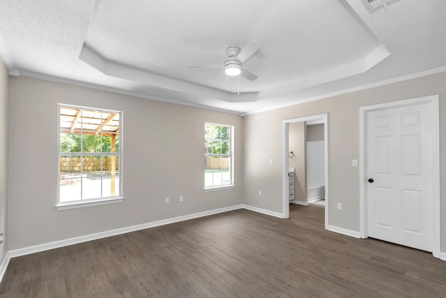 unfurnished bedroom with a textured ceiling, a raised ceiling, ceiling fan, dark wood-type flooring, and multiple windows