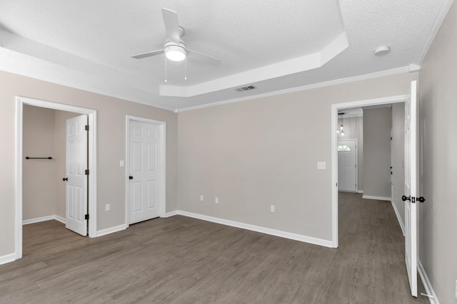 unfurnished bedroom featuring ceiling fan, wood-type flooring, a textured ceiling, and a tray ceiling