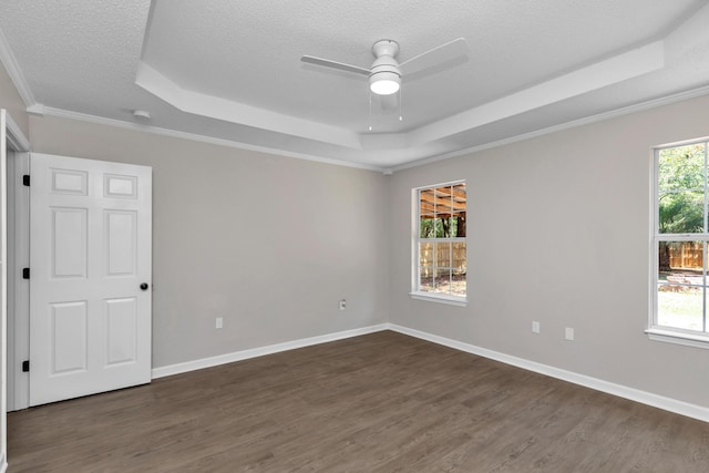 unfurnished room featuring ceiling fan, dark wood-type flooring, a raised ceiling, a textured ceiling, and ornamental molding