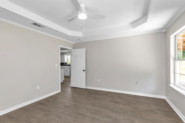 unfurnished room with a tray ceiling, ceiling fan, dark wood-type flooring, and a textured ceiling