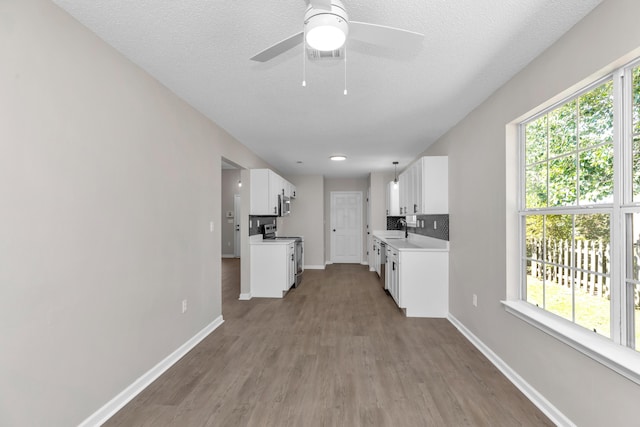 kitchen with tasteful backsplash, stainless steel appliances, sink, white cabinets, and plenty of natural light