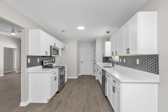 kitchen featuring white cabinets, sink, hanging light fixtures, ceiling fan, and stainless steel appliances