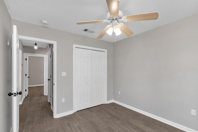 unfurnished bedroom with a textured ceiling, ceiling fan, dark wood-type flooring, and a closet