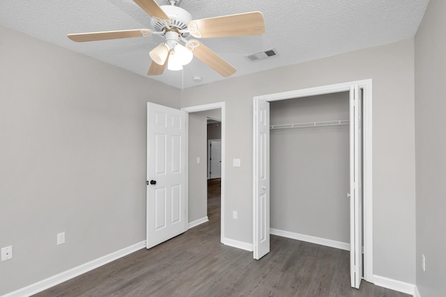 unfurnished bedroom with ceiling fan, dark hardwood / wood-style flooring, a textured ceiling, and a closet