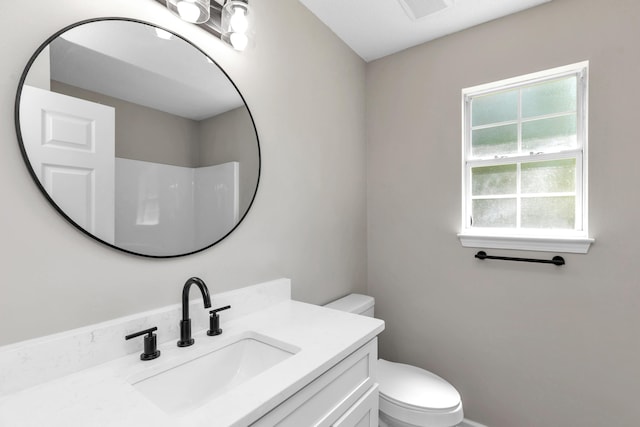 bathroom featuring walk in shower, vanity, and toilet