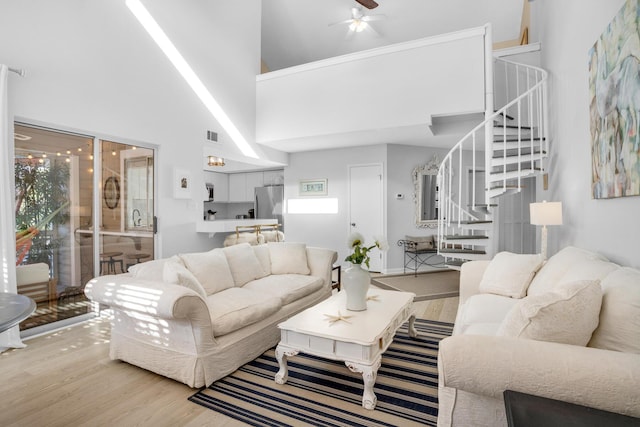 living room with ceiling fan, a high ceiling, and wood-type flooring