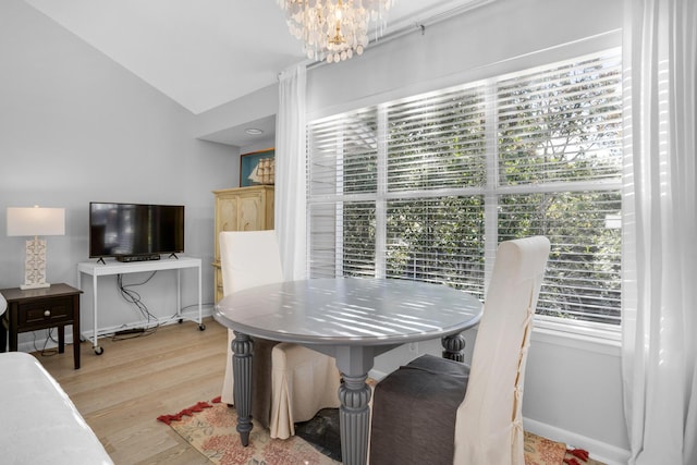 dining room with vaulted ceiling, a notable chandelier, and light hardwood / wood-style flooring