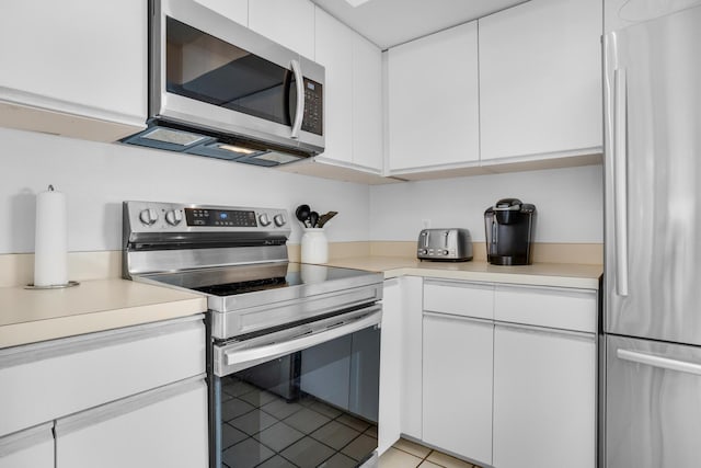 kitchen featuring light tile patterned floors, appliances with stainless steel finishes, and white cabinetry